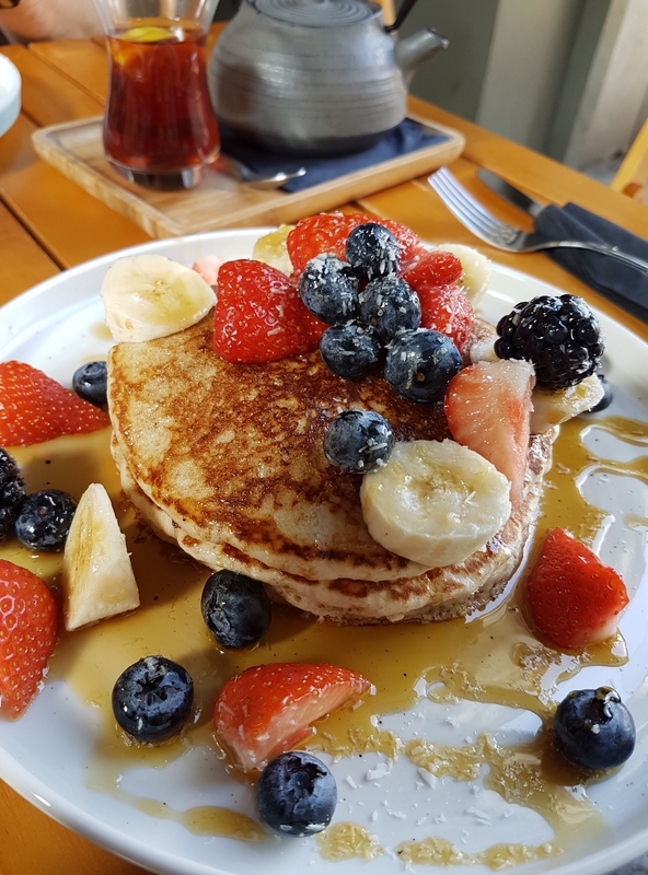 stack of pancakes covered in fruit and maple syrup